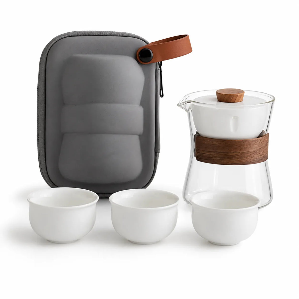 A tea set set including a gray hard carrying case with a brown leather strap, a glass teapot with a brown wooden handle, and three white ceramic teacups on a white background.