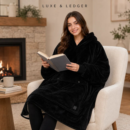 A woman sits in a cream armchair by a fireplace, wrapped in a plush black hooded robe and holding an open book. The brand name 'LUXE & LEDGER' appears at the top of the image.