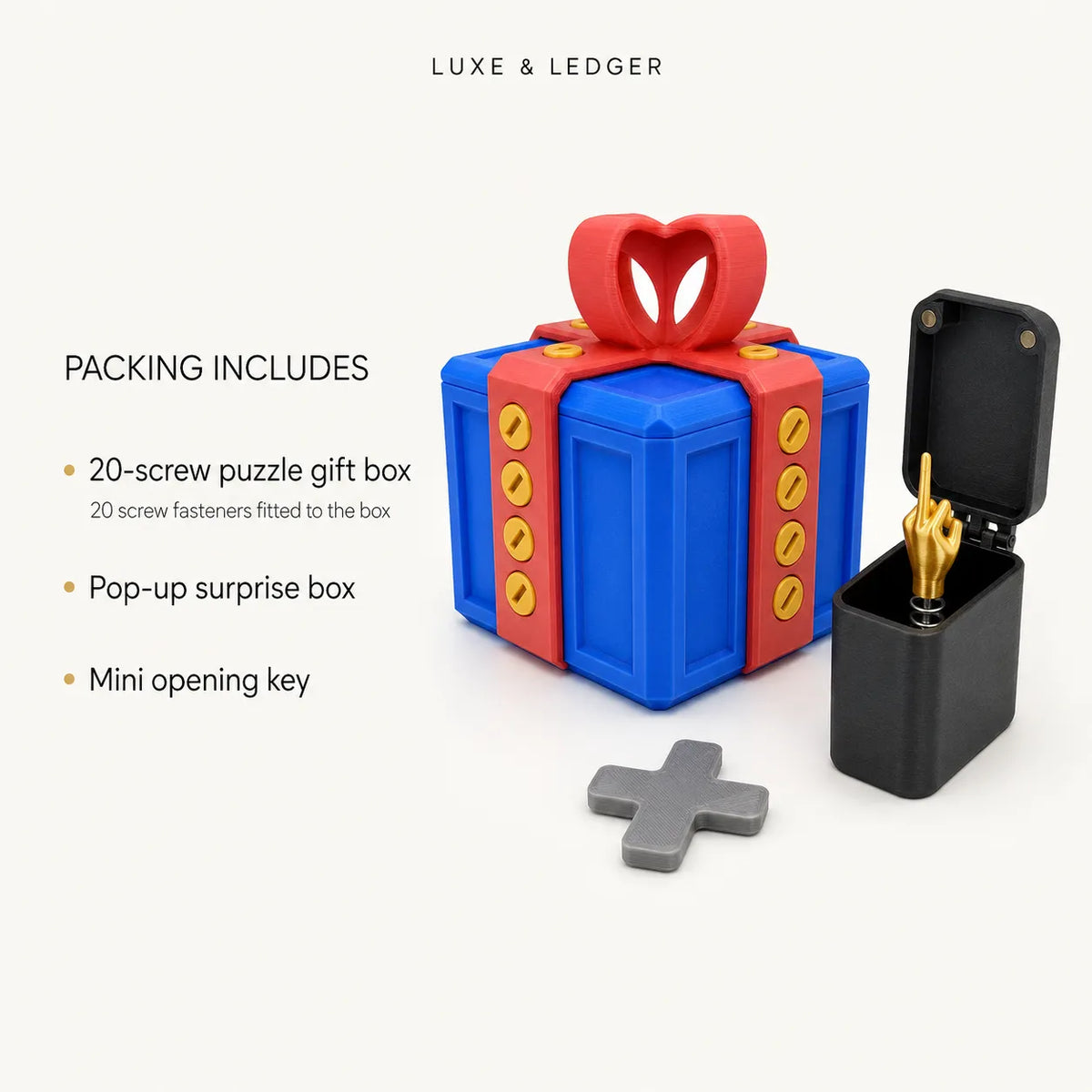 Luxe & Ledger puzzle gift box set on a light beige background, featuring a blue and red gift box with a red heart-shaped bow, a black pop-up surprise box with a gold-finished finger, a gray key, and text detailing the included accessories.