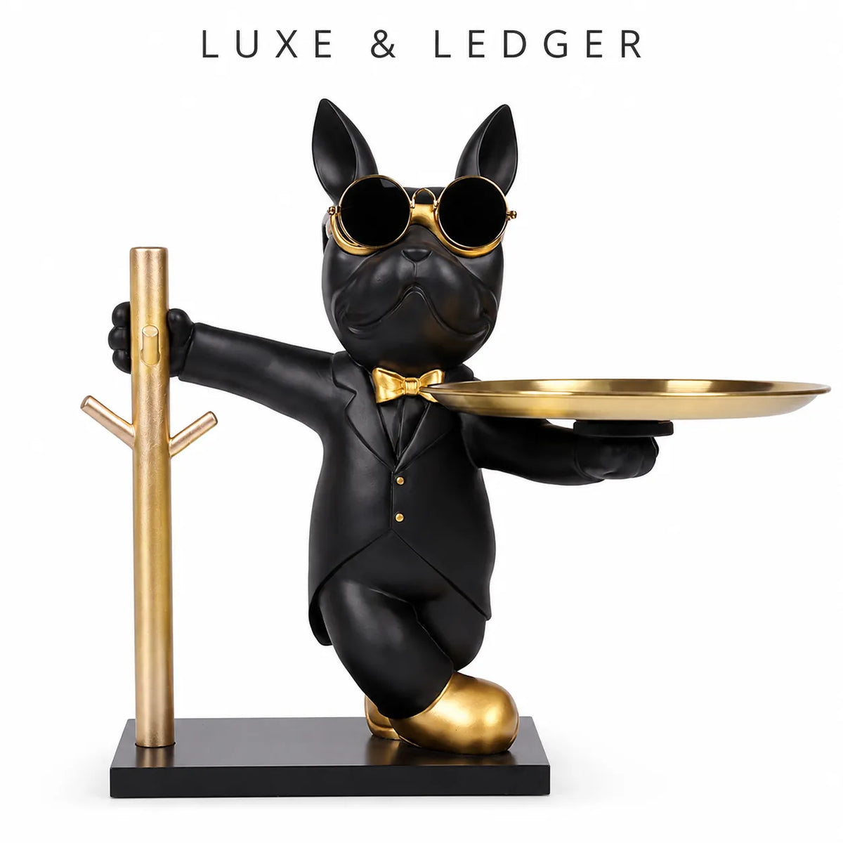 A decorative figurine of a black French bulldog wearing gold sunglasses, a black tuxedo, and a gold bow tie, holding a round gold tray while standing on a black base next to a gold coat rack. The text 'LUXE & LEDGER' is printed at the top.