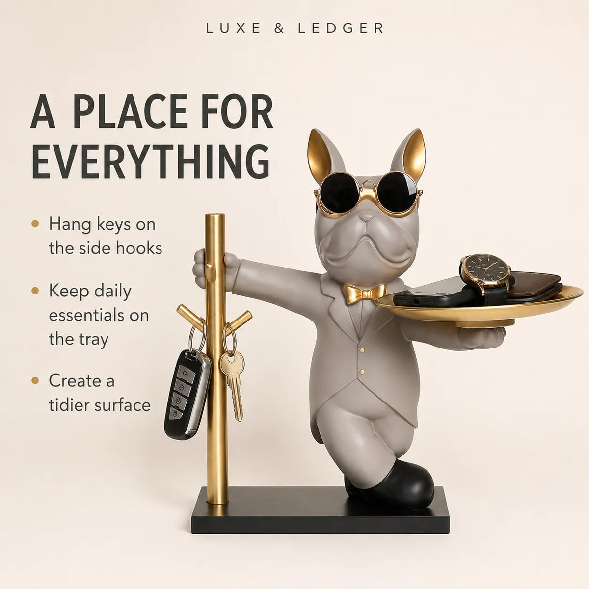 A decorative figurine of a gray cat dressed in a gray suit with gold sunglasses, bow tie, and shoes, holding a gold tray with a watch while standing on a black base. The figurine is shown with a gold key holder pole and keys, with marketing text on the left on a light beige background.