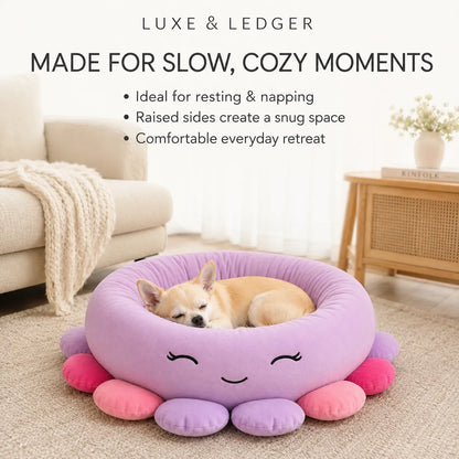 A small tan dog rests inside a round lavender pet bed with pink and purple octopus-like legs and a smiling face. The scene is set in a softly lit living room with a sofa, blanket, side table, and text at the top reading 'LUXE & LEDGER MADE FOR SLOW, COZY MOMENTS'.