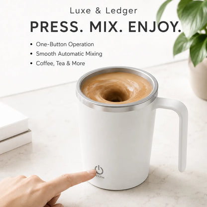 A white electric mug with a handle and stainless steel rim, shown on a light marble surface with a hand pressing the power button. The coffee inside is stirred by an invisible magnetic wand.
