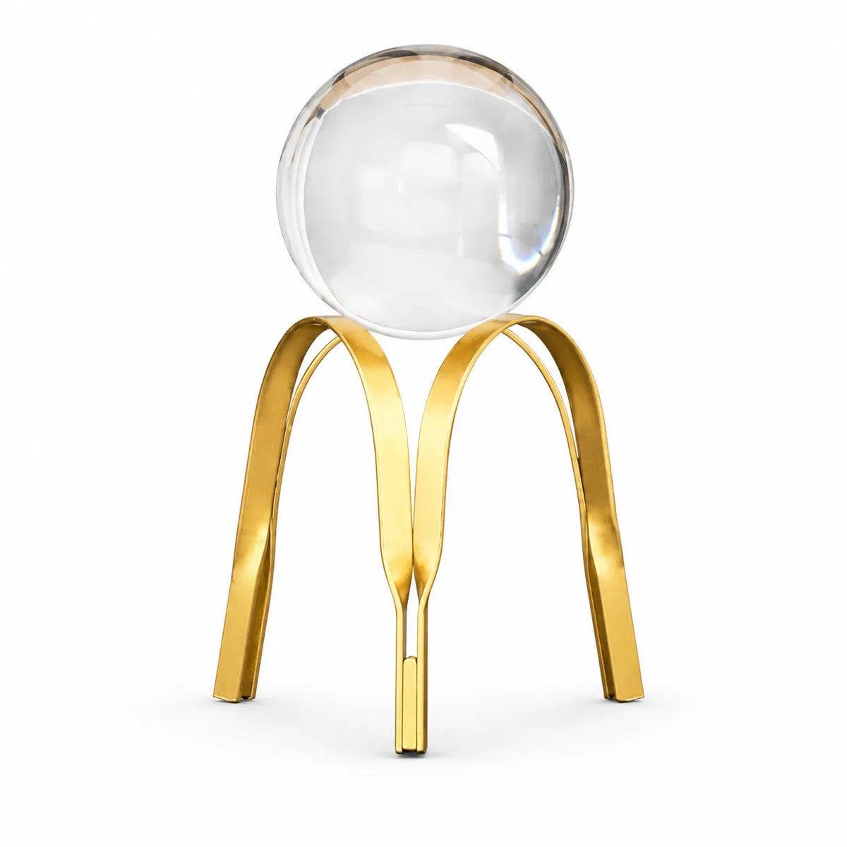 A modern decorative sculpture featuring a clear glass sphere balanced on a polished gold metal tripod base, set against a solid white background.