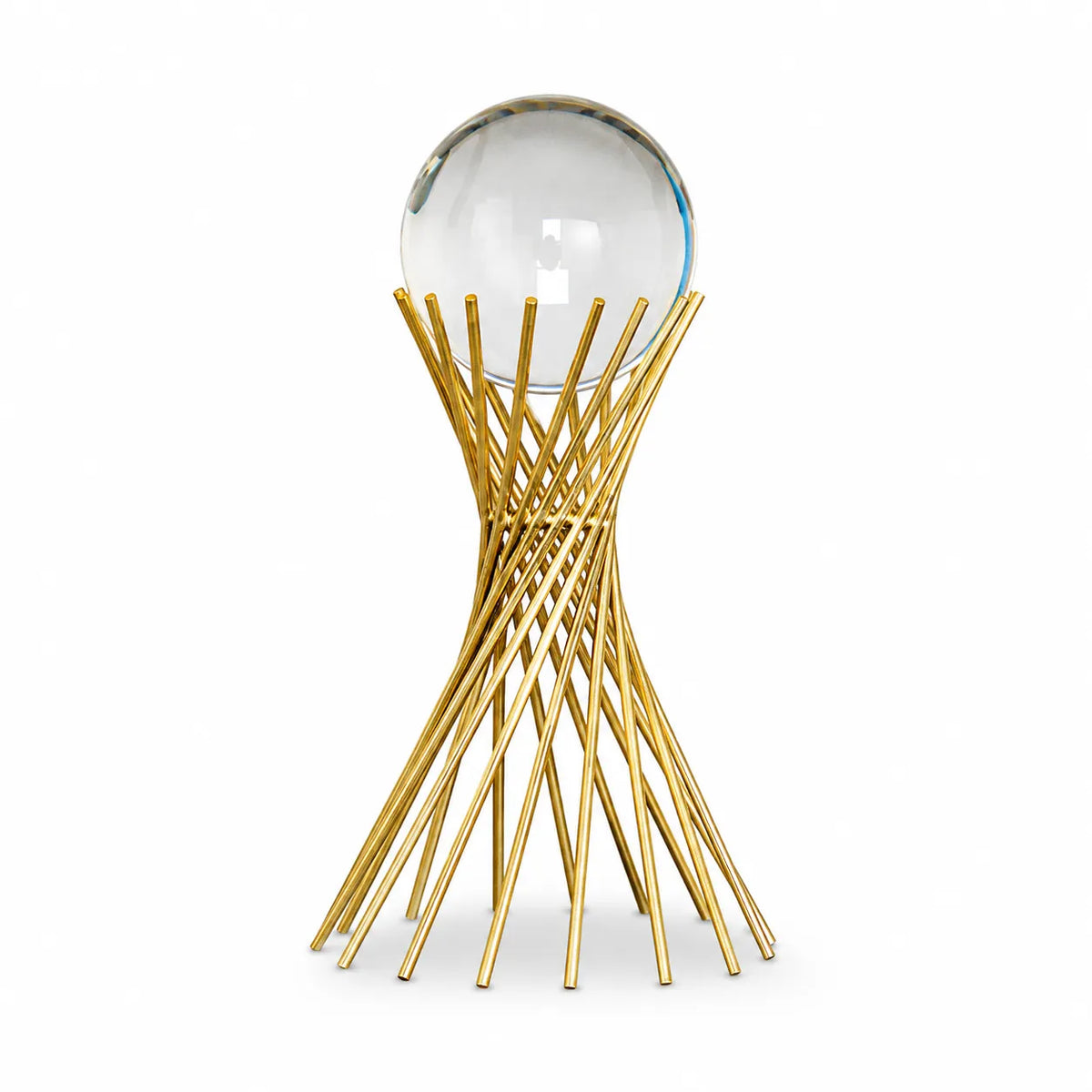 A modern table sculpture featuring a clear glass sphere resting on a sculptural base made of interwoven gold metal rods, set against a plain white background.