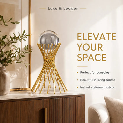A gold wire geometric console table holding a clear glass sphere, styled in a modern living room setting with a wooden cabinet, a vase with green leaves, and a beige armchair. Text on the right reads 'Luxe & Ledger' and 'ELEVATE YOUR SPACE'.