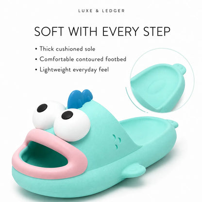 A turquoise fish-shaped slipper with a pink mouth and white cartoon eyes, shown on a white background with marketing text and a circular inset detail of the footbed.