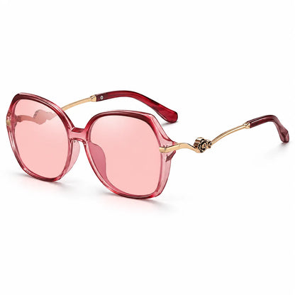 Oversized square sunglasses with translucent pink lenses, a translucent red frame, and gold metal temples with a decorative emblem, shown on a white background.