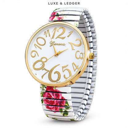 A wristwatch with a silver-toned metal link bracelet featuring pink and green floral patterns, a gold-tone round case, and a white dial with large gold Arabic numerals. The brand name 'Geneu' is visible on the dial, and 'LUXE & LEDGER' is printed at the top.