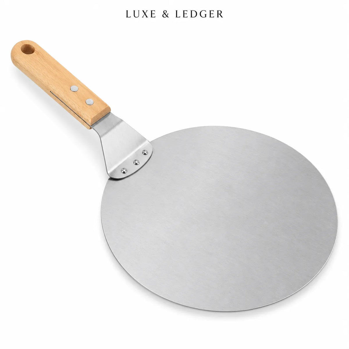 A round metal pizza peel with a light wood handle, shown on a clean white background with the brand name 'LUXE & LEDGER' printed at the top.