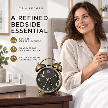 A woman in a bedroom sits in bed holding a mug beside a vintage-style brass alarm clock on a wooden bedside table. Text on the left reads 'LUXE & LEDGER' and 'A REFINED BEDSIDE ESSENTIAL' with feature callouts.
