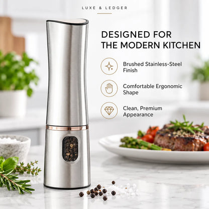 A tall brushed stainless steel pepper mill with a rose gold accent band, shown on a kitchen countertop beside a plate of steak and vegetables. Text on the image reads 'LUXE & LEDGER' and 'DESIGNED FOR THE MODERN KITCHEN' with feature callouts.