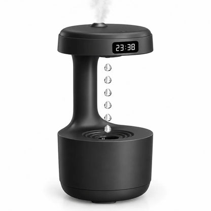 A matte black tabletop humidifier and diffuser with a digital LED clock displaying 23:38, emitting a fine mist from the top and showing water droplets falling in the center, set against a plain white background.