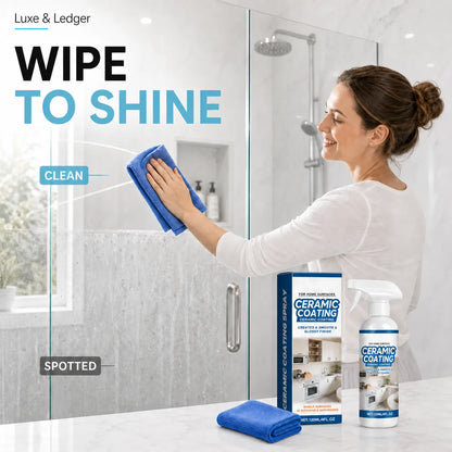 A woman in a white top wipes a glass shower door with a blue cloth in a bright bathroom. In the foreground, a boxed set and spray bottle of Luxe & Ledger Ceramic Coating and Protector, along with a folded blue cloth, are displayed on a white countertop.