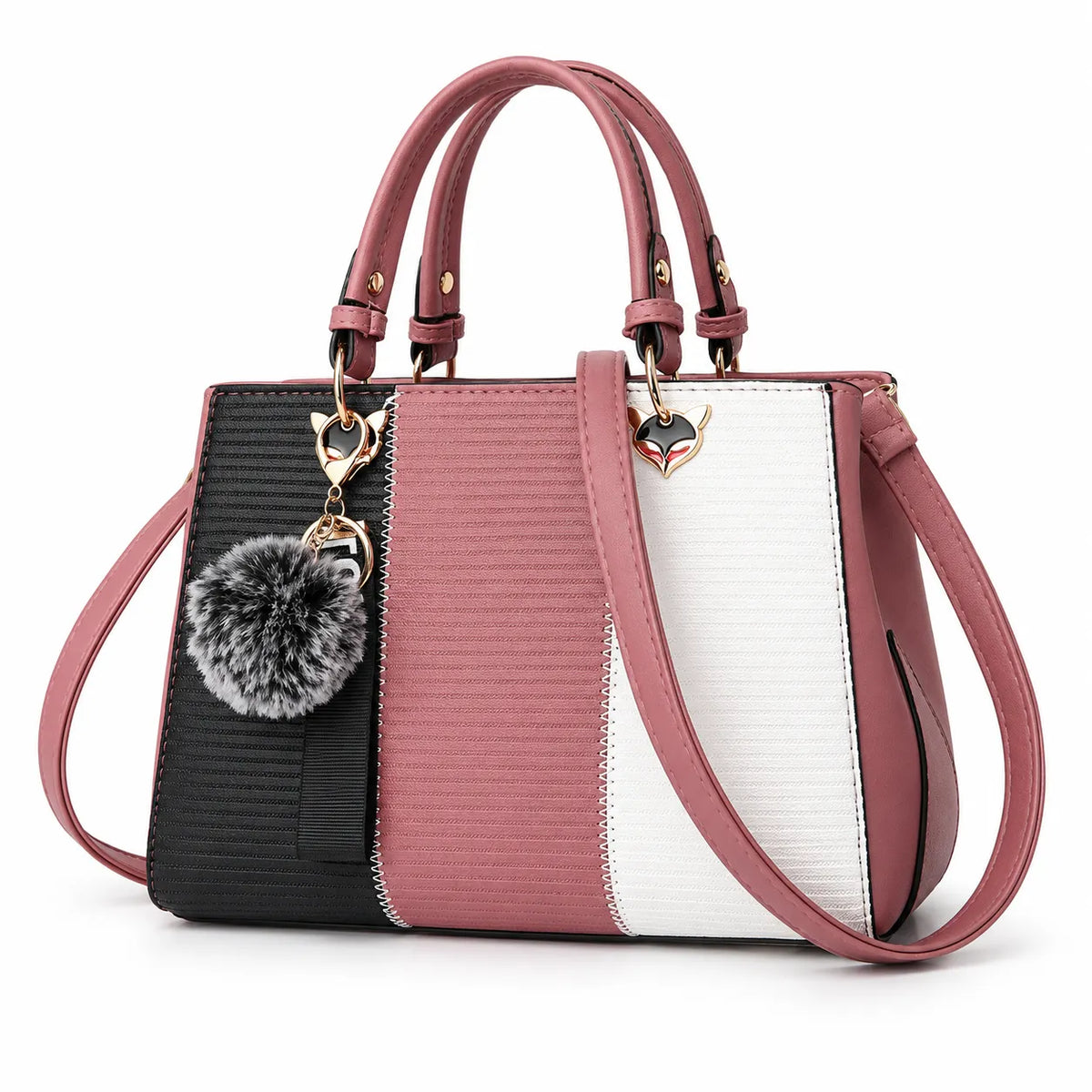 A structured handbag with a color-blocked design featuring black, dusty rose, and white textured panels, with matching rose handles and a shoulder strap. It is adorned with gold-tone hardware, a heart-shaped charm, and a gray faux-fur pom-pom keychain, set against a plain white background.