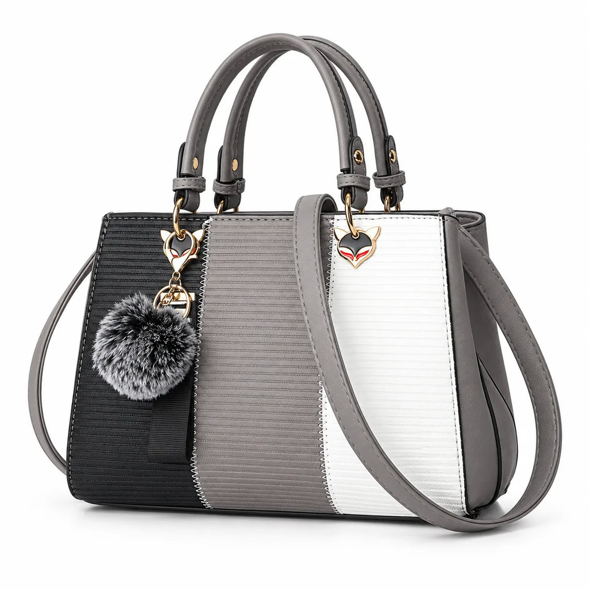 A structured handbag with a three-tone color-blocked design in black, gray, and white textured panels, featuring gray leather handles, a shoulder strap, a gray faux-fur pom-pom charm, and a small fox-head metal logo.