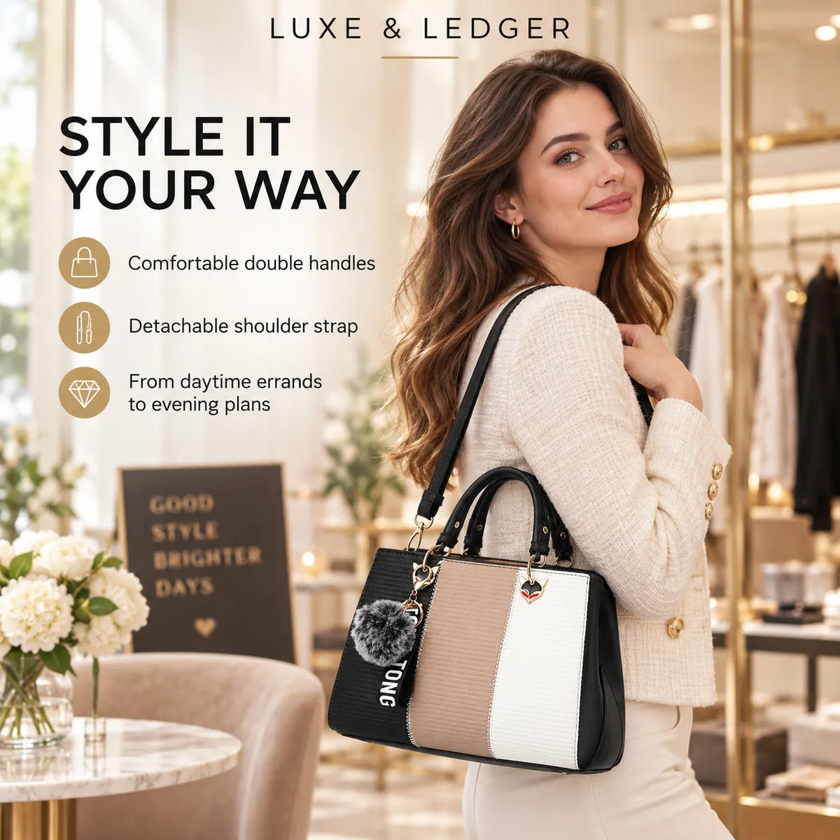 A woman in a cream knit sweater and skirt carries a Luxe & Ledger handbag in a boutique setting. The bag features a color-blocked design in black, beige, and white, with a black fluffy pom-pom charm and gold-tone hardware.