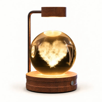 A modern magnetic levitation table lamp with a glowing heart-shaped cloud inside a clear glass sphere, set on a round wooden base with a matching wooden lamp arm, shown against a solid white background.