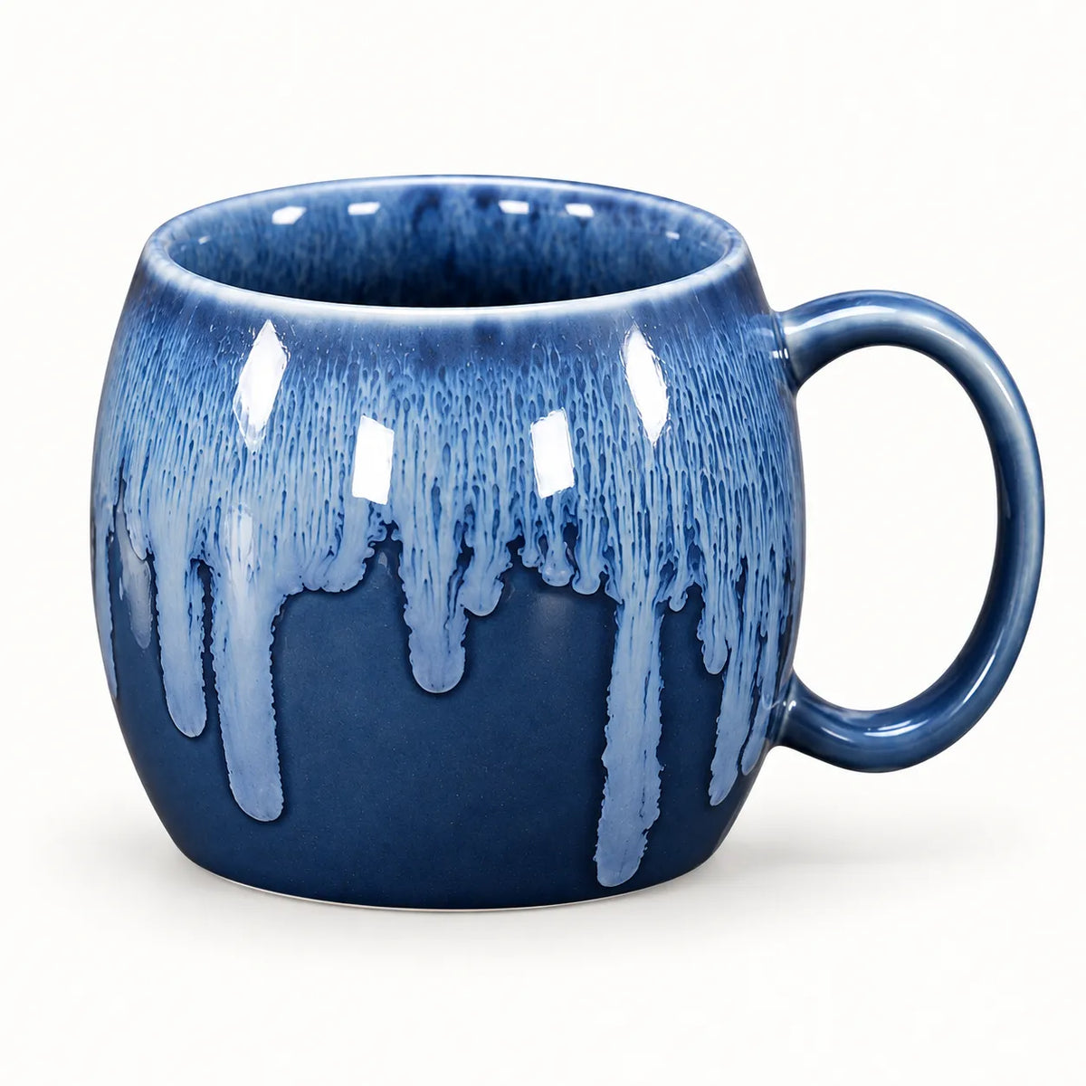 A ceramic mug with a rounded body and a C-shaped handle, featuring a deep blue base glaze with a lighter blue dripping glaze effect around the rim and handle, set against a plain white background.