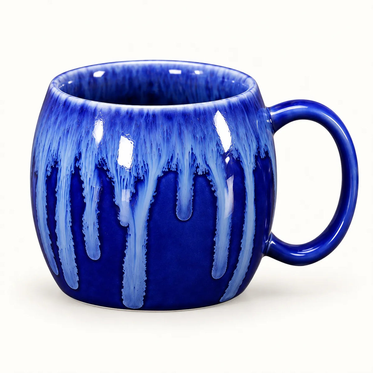 A cobalt blue ceramic mug with a dripping glaze effect in lighter blue and white, shown on a clean white background.