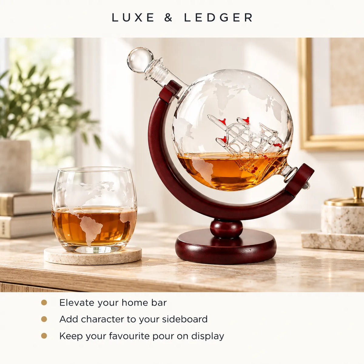A Luxe & Ledger globe-shaped glass decanter with a ship design and amber liquid on a dark wood stand, displayed on a tabletop next to a matching glass tumbler. The scene is styled in a bright, modern interior with text overlays at the top and bottom.