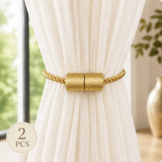 Two gold curtain tiebacks with a rope-textured design and magnetic center clasp, shown tied around a white curtain in a bright room. A '2 PCS' badge is in the lower-left corner.