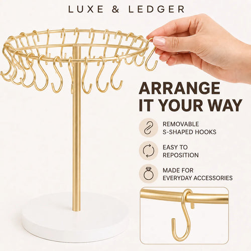 Gold jewelry stand with a white circular base and multiple S-shaped hooks, shown with a hand adjusting a hook. Text reads 'LUXE & LEDGER' and 'ARRANGE IT YOUR WAY' with feature icons.