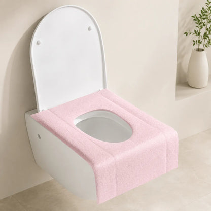A pink textured toilet seat cover with an integrated oval opening, shown fitted on a white wall-mounted toilet in a clean, modern bathroom setting.