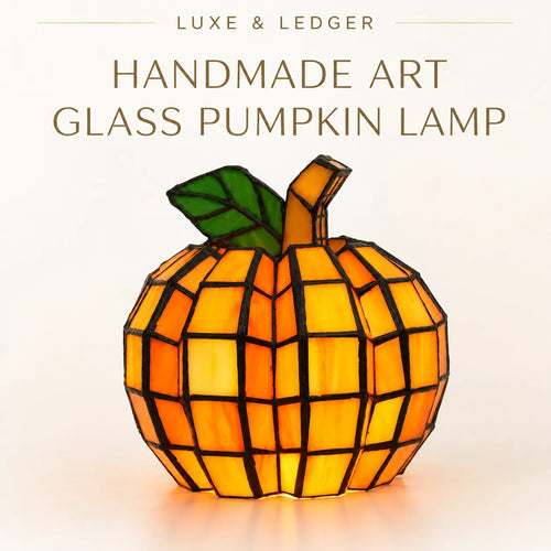 A handmade geometric glass pumpkin lamp with orange and yellow stained-glass panels, a green leaf, and a brown stem, shown against a light beige background with the text 'LUXE & LEDGER HANDMADE ART GLASS PUMPKIN LAMP' at the top.