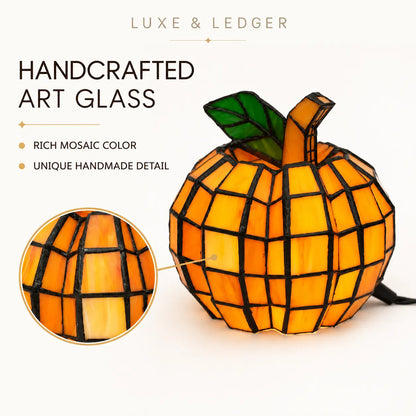 A handcrafted mosaic art glass pumpkin lamp by Luxe & Ledger, featuring orange and yellow stained-glass panels, a green leaf, and black grid lines. The image includes marketing text and a circular detail inset showing the mosaic pattern.