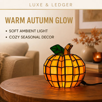 A stained-glass pumpkin-shaped lamp glowing with a warm orange and yellow light, placed on a wooden table in a cozy living room setting. Text on the image reads 'LUXE & LEDGER' and 'WARM AUTUMN GLOW' with bullet points describing soft ambient light and cozy seasonal decor.
