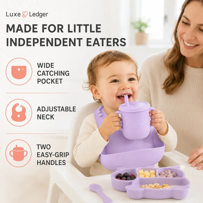 A child wearing a lavender bib and holding a matching sippy cup with straw in a high chair, with a woman smiling beside them. The image includes marketing text and icons for Luxe Ledger, highlighting features like a wide catching pocket, adjustable neck, and two easy-grip handles.