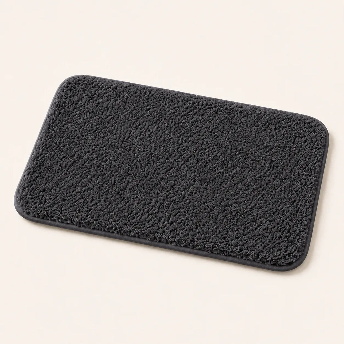 A rectangular navy blue bath mat with rounded corners and a textured, looped surface, shown on a plain off-white background.