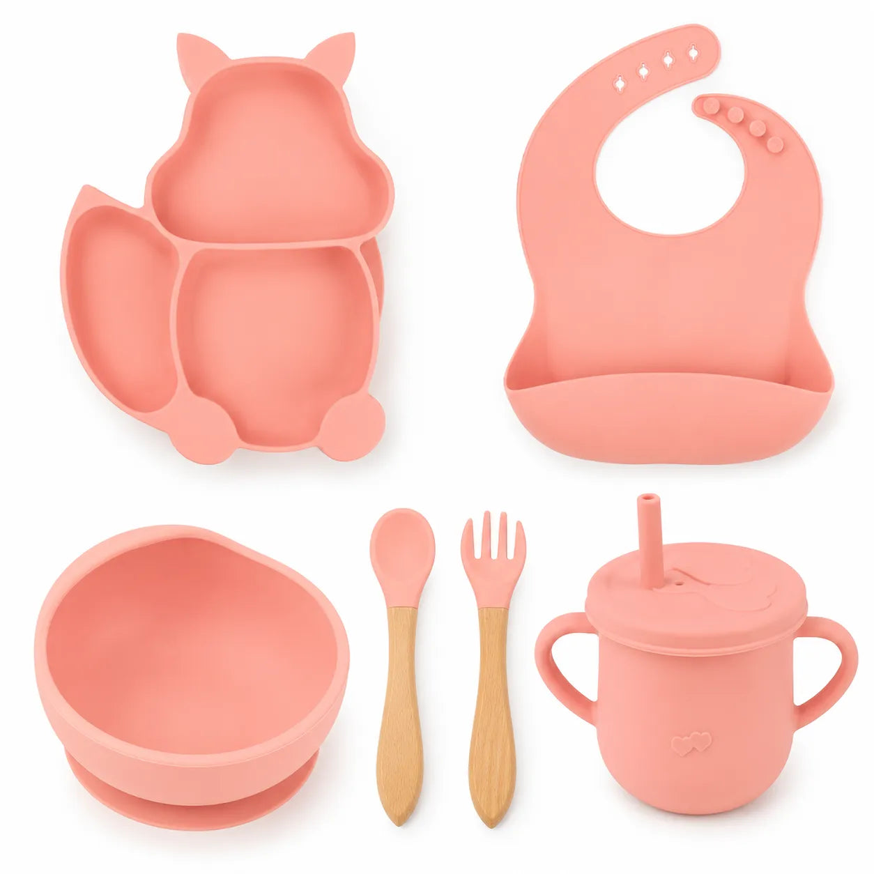 A baby feeding set in soft coral pink silicone and natural wood, including a cat-shaped divided plate, a curved bib, a bowl, a sippy cup with straw, a spoon, and a fork, arranged on a white background.