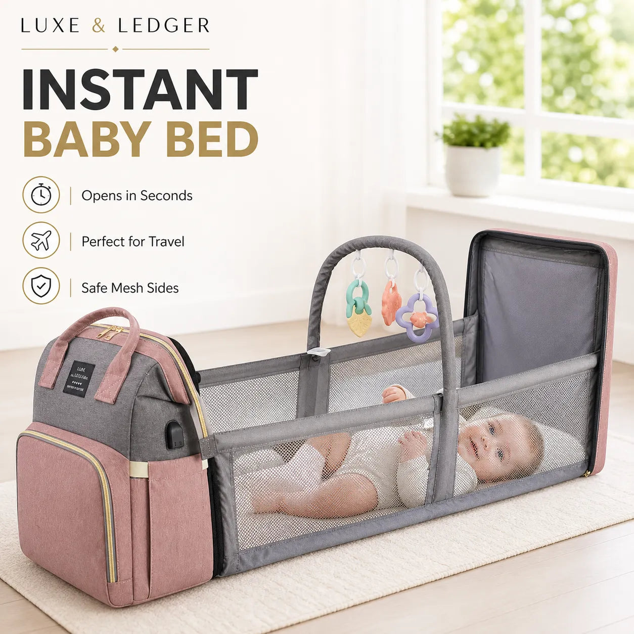 Portable baby bed with pink and gray design, featuring a baby inside, on a light wooden floor.