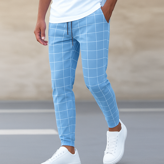 Person wearing blue checkered pants and white sneakers on a blurred street background