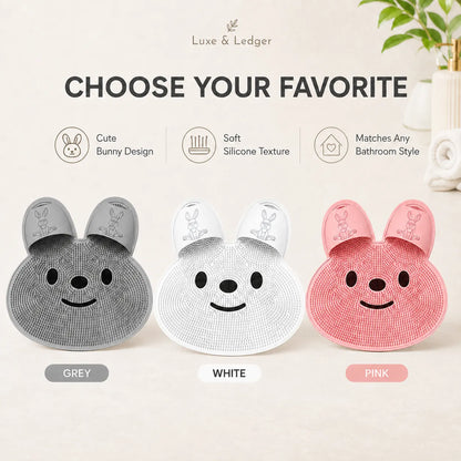Three bunny-shaped slippers in grey, white, and pink with 'Luxe & Ledger' branding.