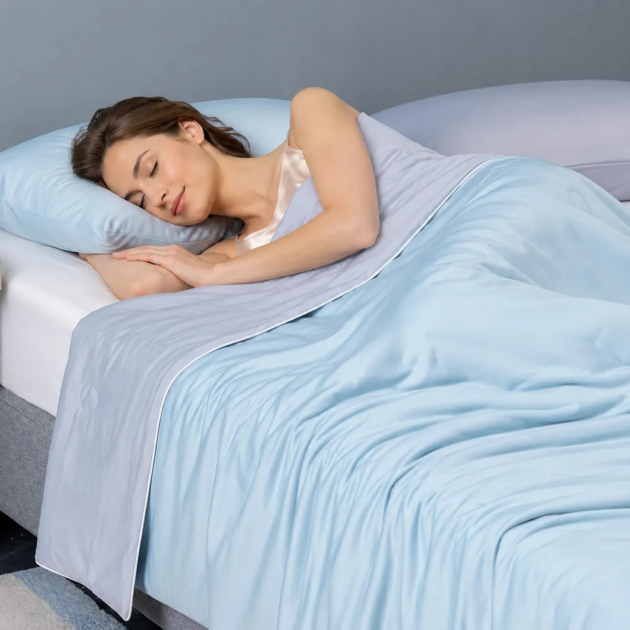 Woman sleeping on a bed with a light blue comforter and pillow