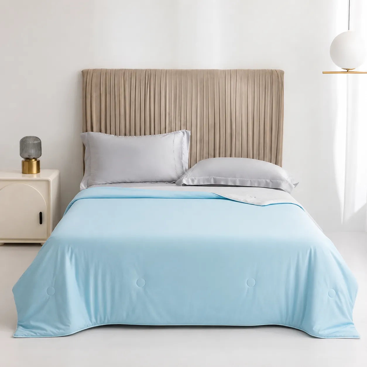 Bed with light blue comforter and beige headboard in a room setting
