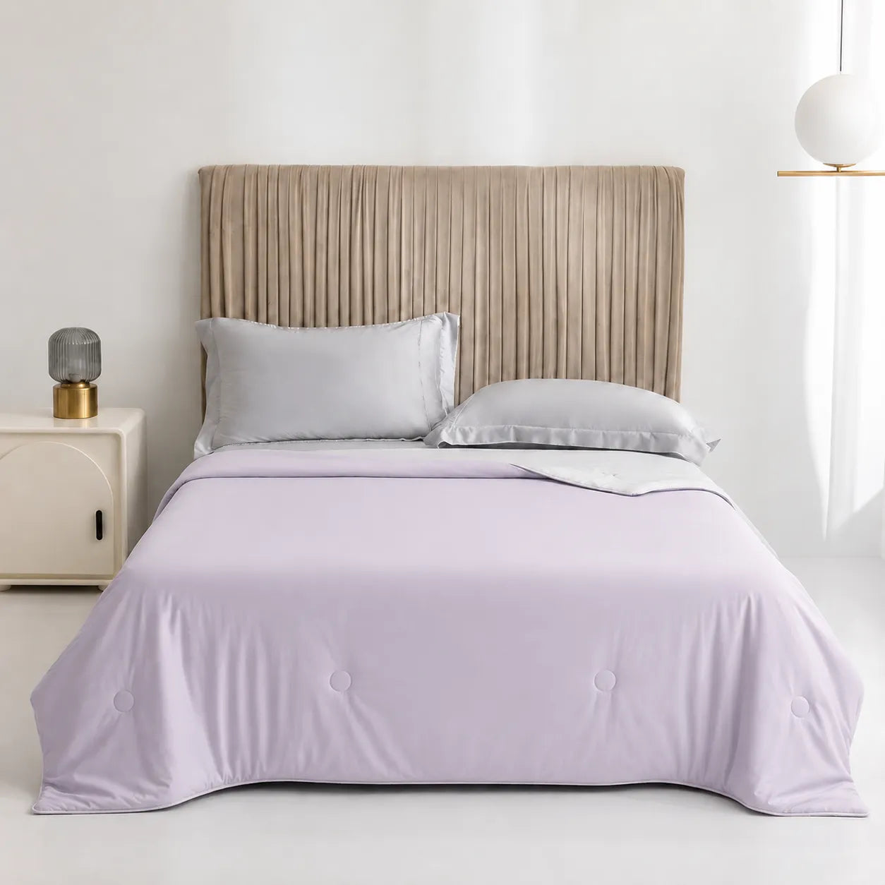 Bed with lavender comforter and pillows in a bedroom setting