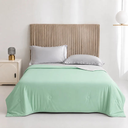 Bed with mint green comforter and beige headboard in a bright room