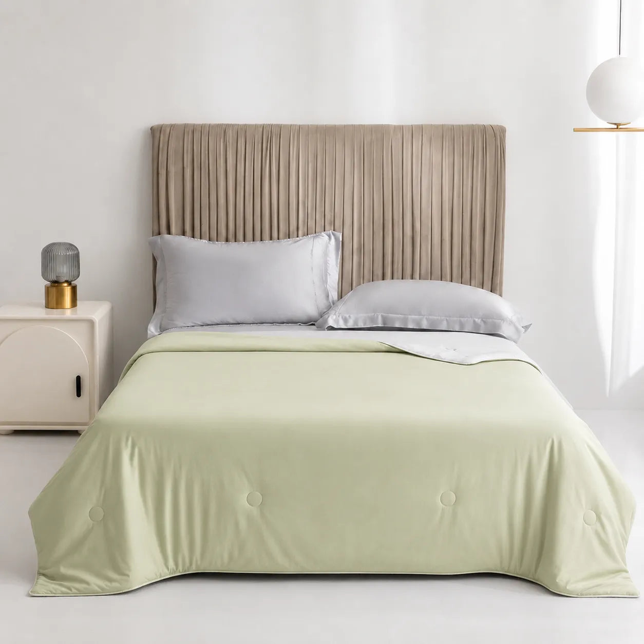 Bed with light green bedding and beige headboard in a minimalistic room.