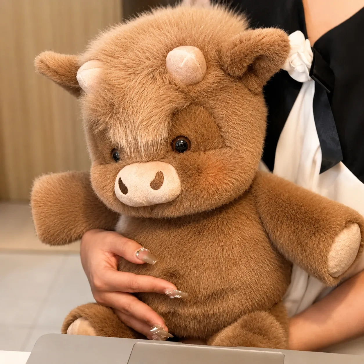 Brown plush toy resembling a boar held by a person with a blurred background