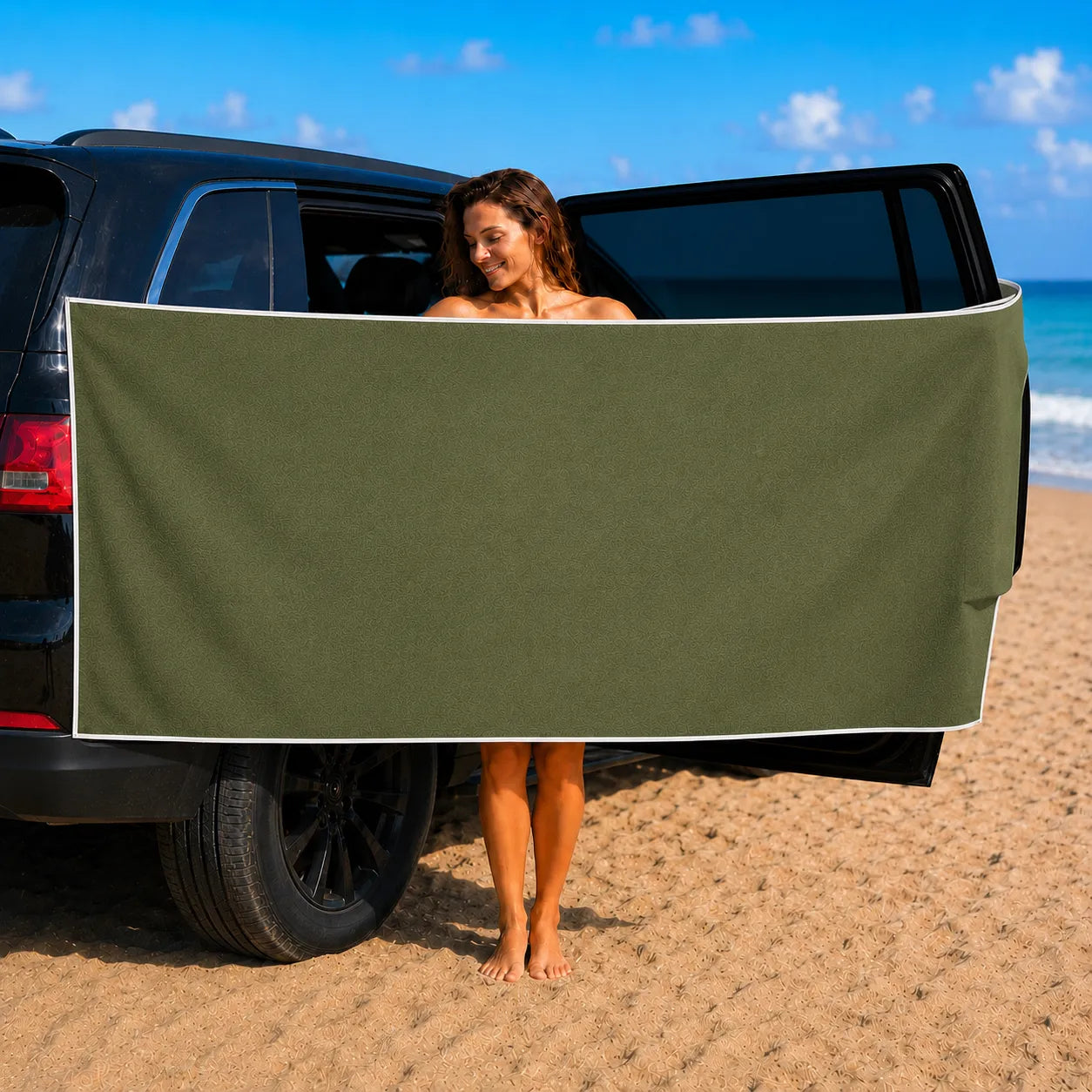 Person standing behind a car with a green cover on a beach