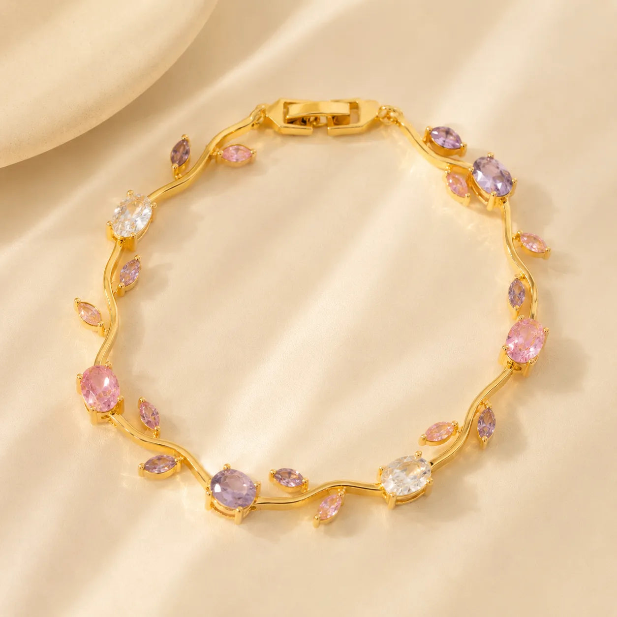 Gold bracelet with colorful gemstones on a beige background