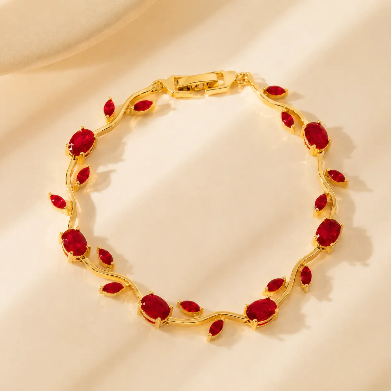 Gold bracelet with red gemstones on a beige background