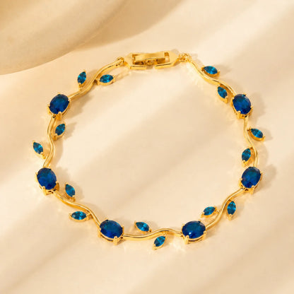 Gold bracelet with blue gemstones on a beige background