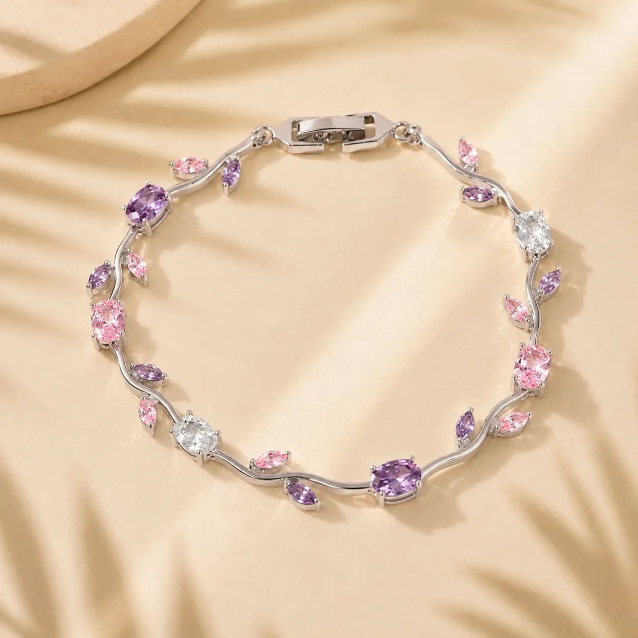 Silver bracelet with pink and purple gemstones on a beige fabric background