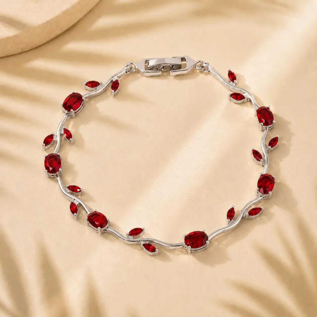 Silver bracelet with red gemstones on a beige background