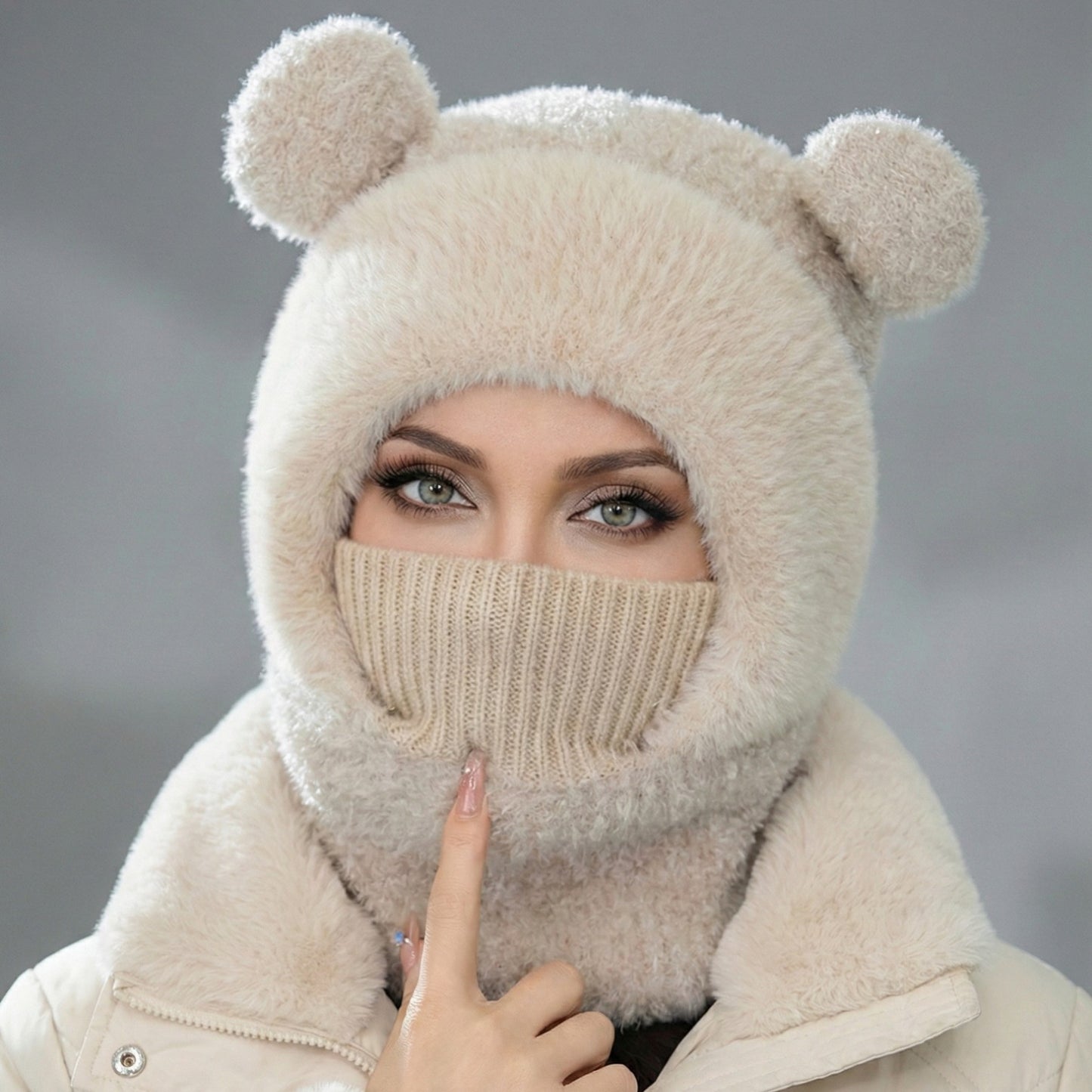 Person wearing a beige knitted balaclava with bear ears against a gray background